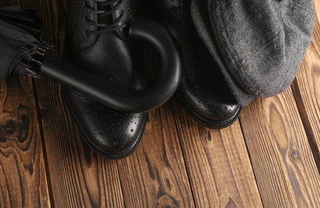 Gentleman's accessories. Men's boots, cap and umbrella on a wooden backgroundの写真素材