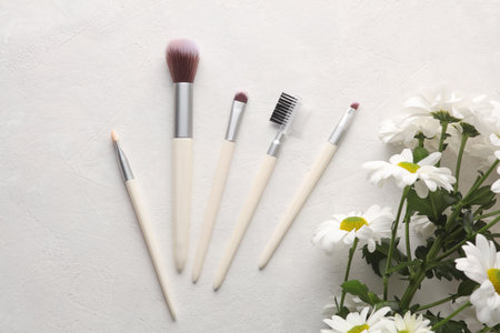 Flowers Bouquet with a set of makeup brushes on a white concrete background