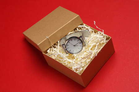 Wrist watch in craft box with filler on red background. Product packagingの写真素材