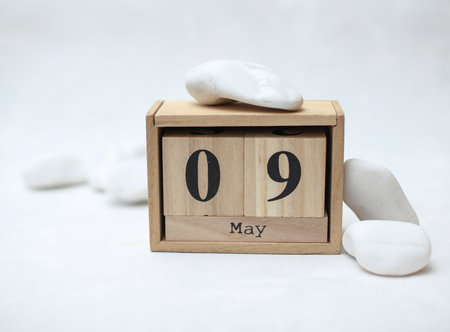 Wooden block calendar with date May 9 on a concrete background with pebbles