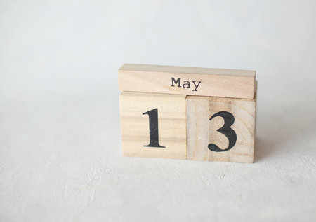 Wooden block calendar with date May 13 on a concrete background