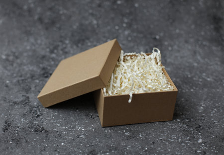 Cardboard craft box with filler on concrete background