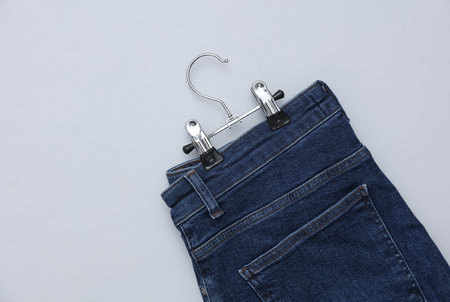 Blue jeans hanging on a hanger, gray background