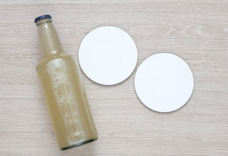 Coasters with beer bottle. White round mockups on a wooden table