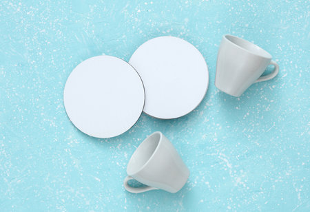 Coasters with ceramic cups, white round mockups on blue concrete backgroundの写真素材
