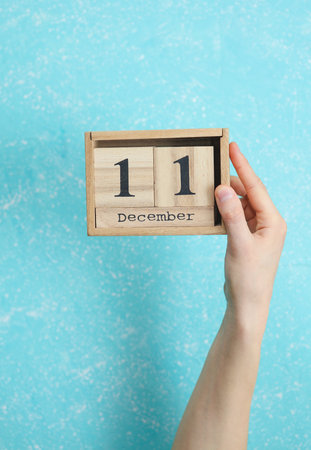 woman's hand holds wooden block calendar with the date December 11