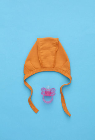 Newborn baby hat and pacifier on blue backgroundの写真素材