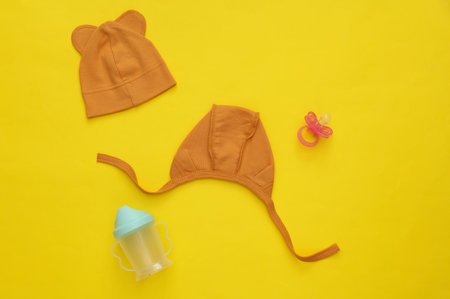 Newborn baby hats and pacifier on yellow background. Flat layの写真素材