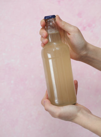 Hands holding bottle of light beer on a pink concrete backgroundの写真素材