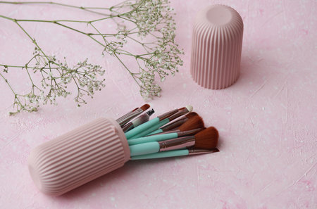 Set of makeup brushes in storage organizer on pink concrete backgroundの写真素材