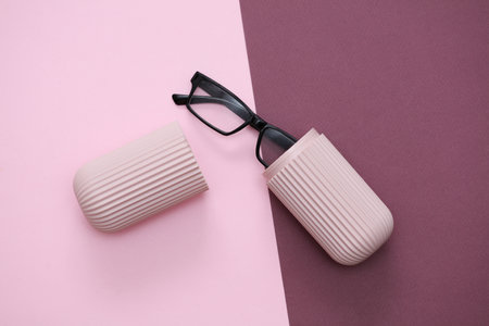 Glasses in a plastic case on a pink burgundy backgroundの写真素材