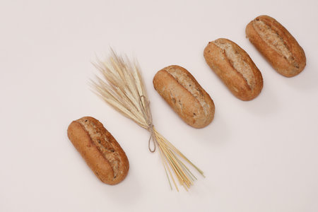 Appetizing rye buns with rye spikelets on a beige background