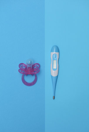 Electronic thermometer and pacifier for newborns on a blue background. Caring for baby's health