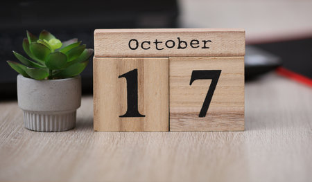 Wooden calendar with the date October 17 on desktop with laptop