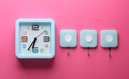 Clock and wall hooks on pink background