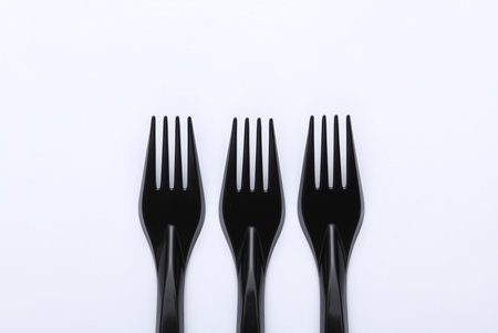 Black plastic forks on a white backgroundの写真素材