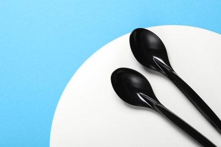 Black plastic spoons on blue white backgroundの写真素材
