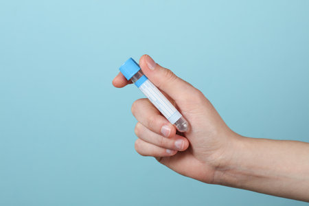 Hand holding empty blood test tube on a blue background