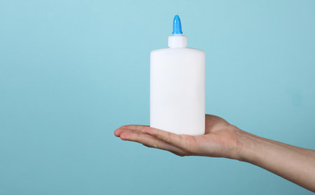 Hand holding glue bottle on blue background