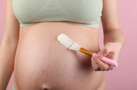 Pregnant woman applying anti-stretch mark cream to her stomachの写真素材