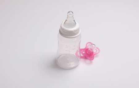 Bottle for feeding newborn and pacifier on white background