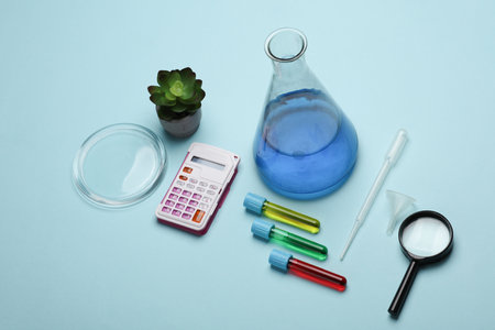 Laboratory glassware (Test tubes with flask) and magnifying glass, calculator on a blue background.の写真素材