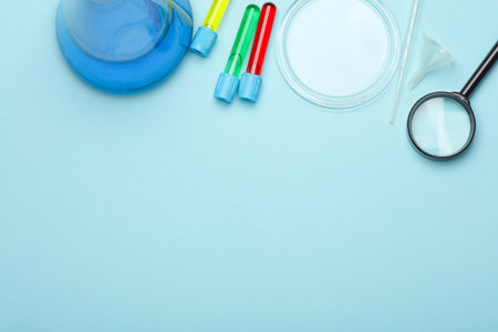 Laboratory glassware (Test tubes with flask) and accessories on blue background. Top view. Flat lay....