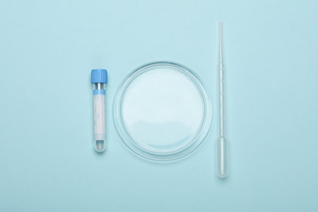 Petri dish with pipette and test tube on blue background. Top view
