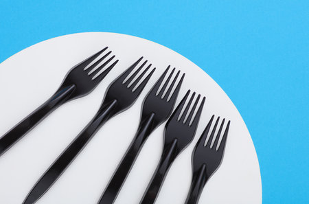 Black plastic forks on blue white backgroundの写真素材