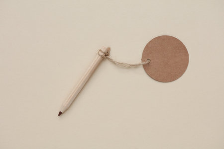 Pencil with round craft price tag on a string. Beige backgroundの写真素材