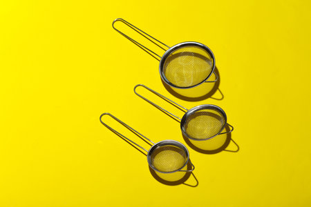 Metal kitchen meshes on a yellow backgroundの写真素材