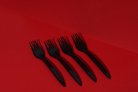 Black plastic forks on a red background with shadow. Creative layoutの写真素材