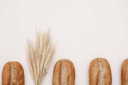 Appetizing rye buns with rye spikelets on a beige backgroundの写真素材