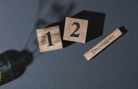 Wooden calendar with the date December 12 on a dark background with shadow. Top viewの写真素材
