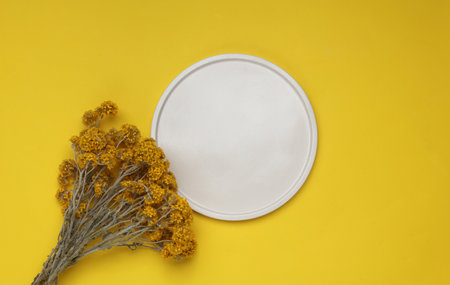 Plaster plate with dry flowers on a yellow background. Top view. Creative layoutの写真素材