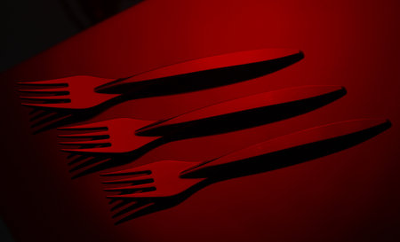 Black plastic forks in red neon lightの写真素材