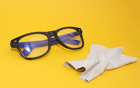 eyeglasses with a cloth for wiping on a yellow backgroundの写真素材