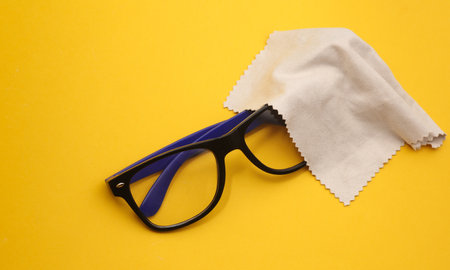 eyeglasses with a cloth for wiping on a yellow backgroundの写真素材
