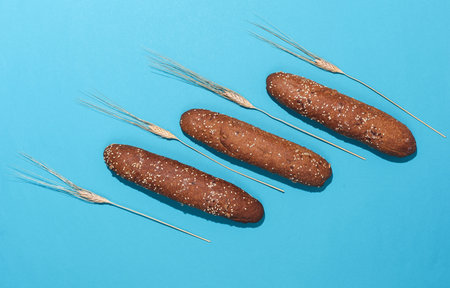 Rye buns, mini baguettes with ears of wheat on blue backgroundの写真素材