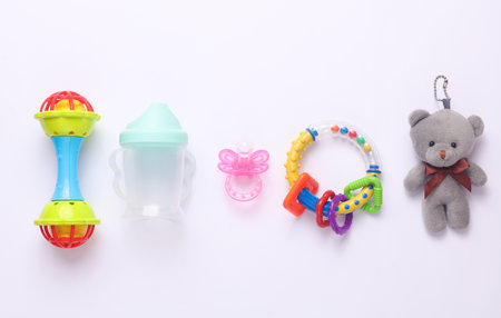 Toys for newborns, feeding accessories on a white background. Flat lay