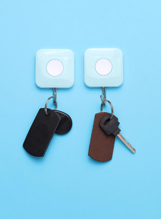 Leather keychains with magnetic and metal keys hanging on a hook on blue backgroundの写真素材