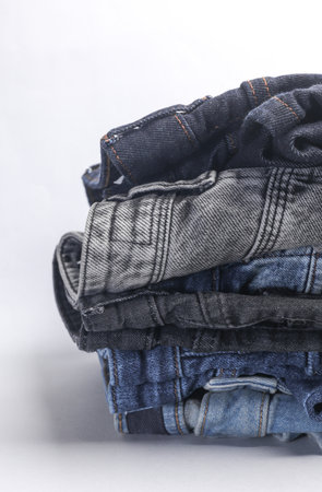 Stack of Many jeans pants on white background
