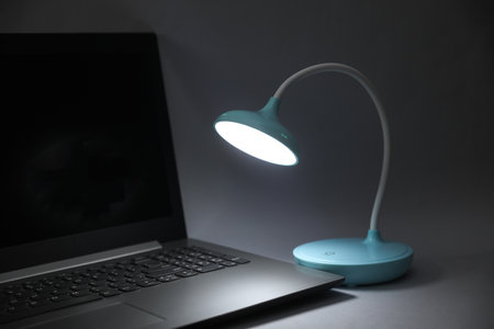 LED table lamp illuminates laptop. Energy saving, business concept, blackout