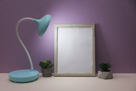 Empty frame with table lamp on purple backgroundの写真素材
