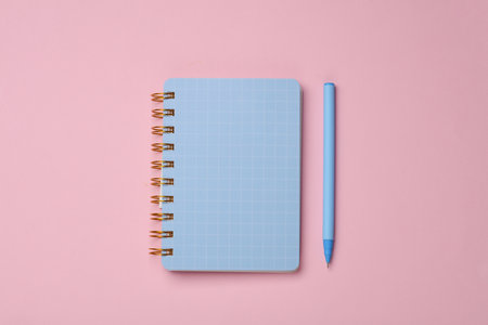 Blue notepad with pen on pink backgroundの写真素材