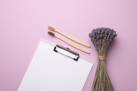 Eco bamboo toothbrushes with clipboard and lavender on purple background. Visit to the dentist, dental care.の写真素材