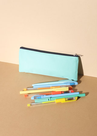 Pencil case with colored pens on a beige background. Creative layout