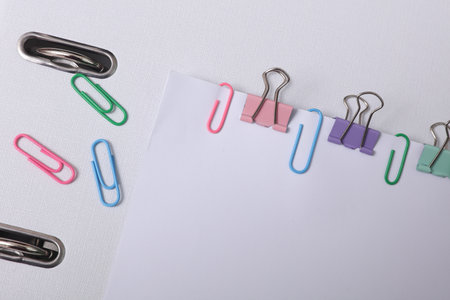 White blank sheets of paper with colored paper clips and bindersの写真素材