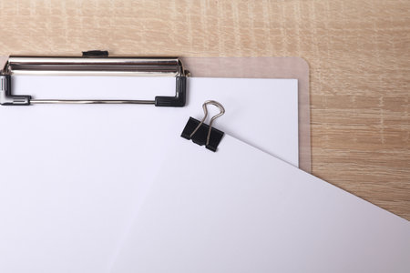 White blank sheet of paper with Black binder and clipboard on the table