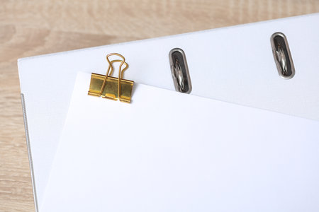 Golden binder with white empty sheet of paper with folder on table. Mockup for design